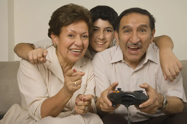 Hispanic grandparents playing video games with grandson