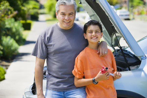 Hispanic father and son standing in front of car with hood up