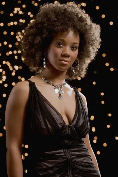 African woman in evening dress with lights in background