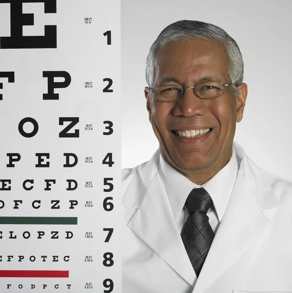 Portrait of Indian male doctor holding eye chart