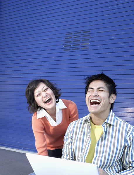Young man and woman laughing at laptop