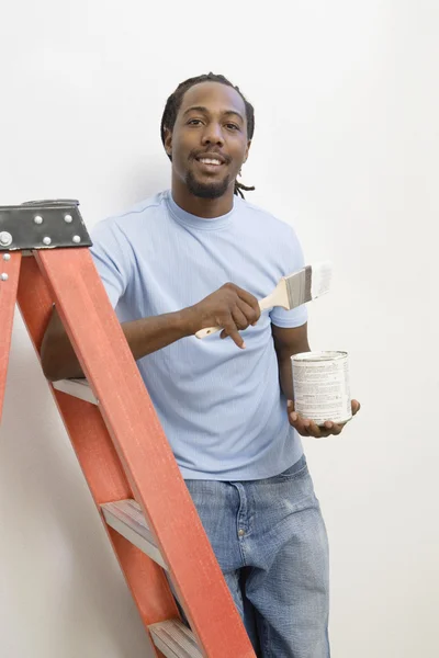 African man on ladder painting