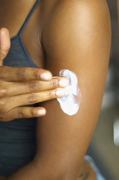 Close up of African woman applying cream to arm