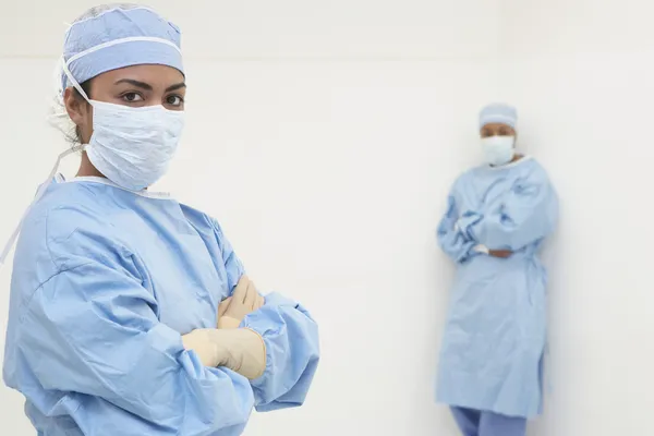 African female surgeon with arms crossed and co-worker in background