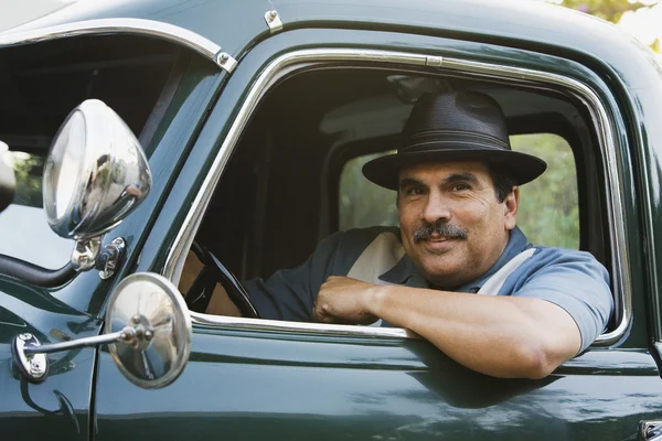 Middle-aged Hispanic man sitting in classic car