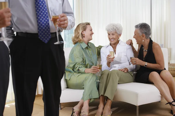 Three senior women talking on sofa at party