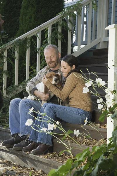 Couple with dog sitting on porch steps
