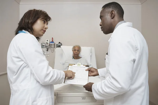 African male and female doctors discussing senior patient\'s chart