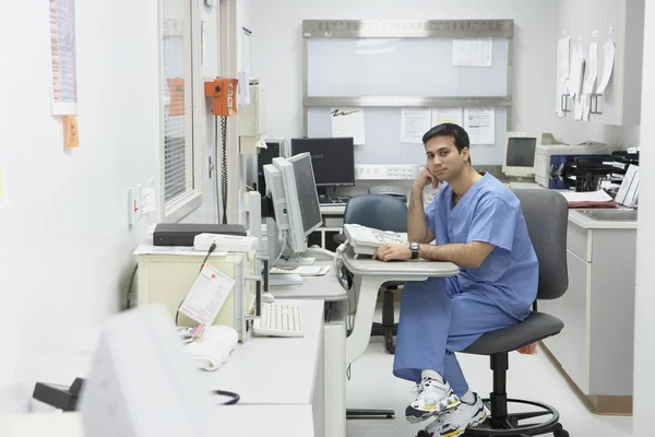 Indian male nurse sitting at computer in medical office