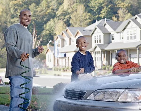 African father and sons washing car in driveway