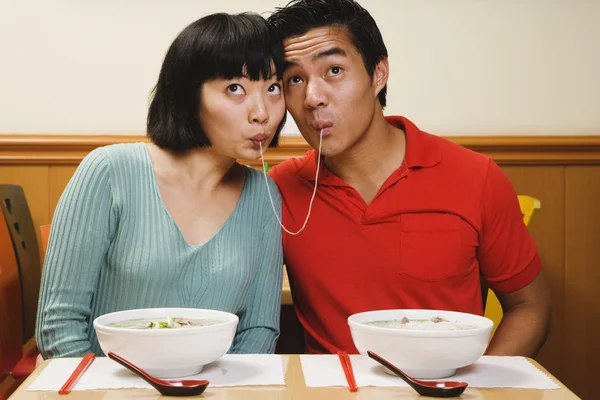Asian couple eating same noodle