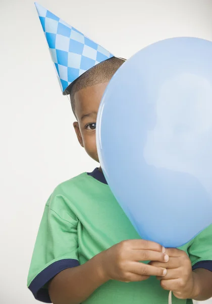 African boy wearing party hat and holding balloon