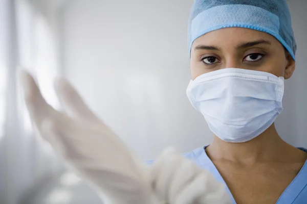 Female doctor putting on surgical gloves