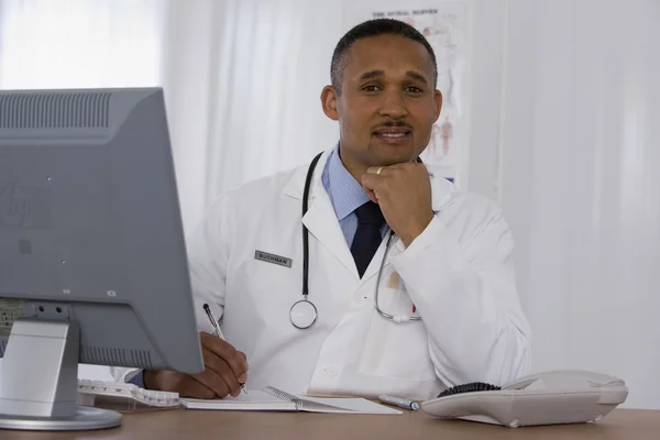 African doctor writing in notebook