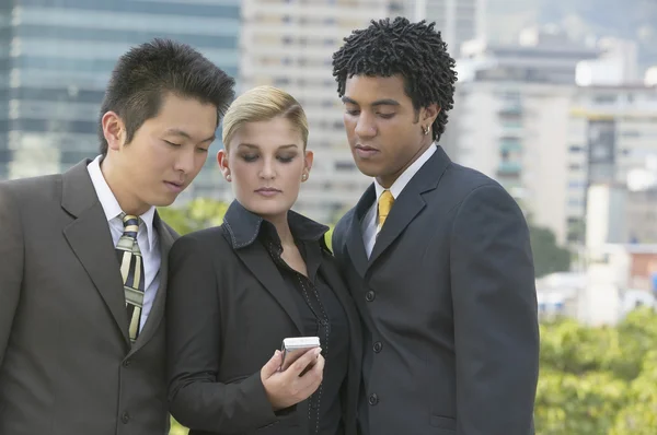Three businesspeople looking at cell phone