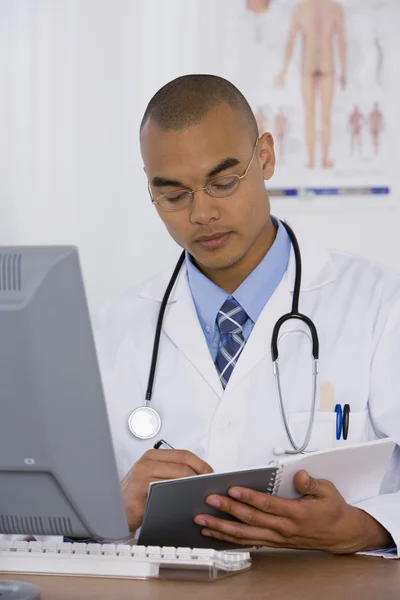 Male doctor writing in notebook