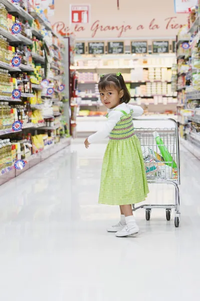 Hispanic girl pushing child\'s shopping cart