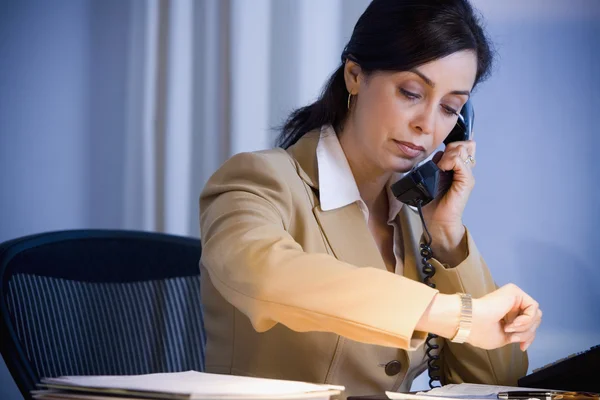 Hispanic businesswoman looking at watch