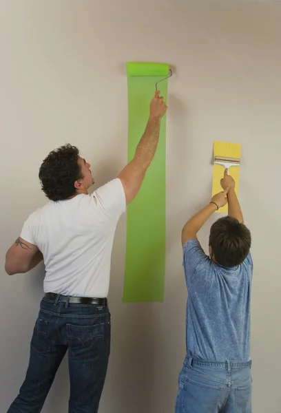 Hispanic father and son painting wall