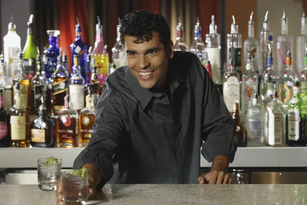 Hispanic male bartender serving drink