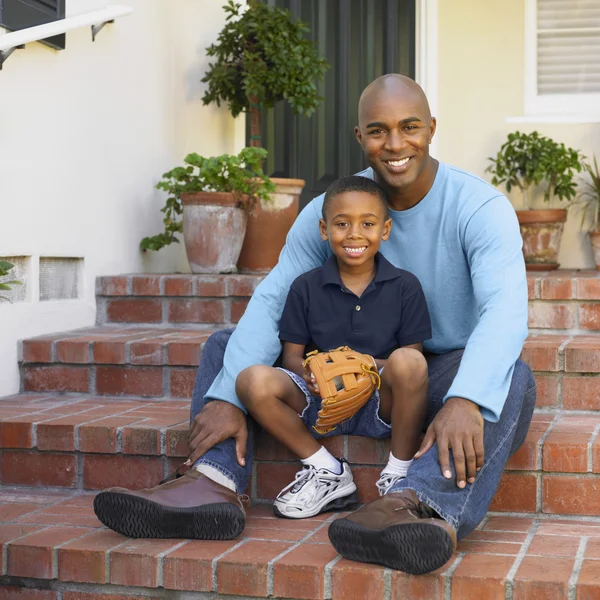 African American father and son sitting on porch steps