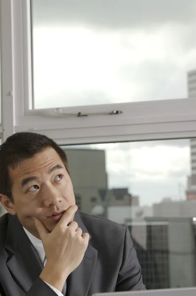 Asian businessman thinking next to window