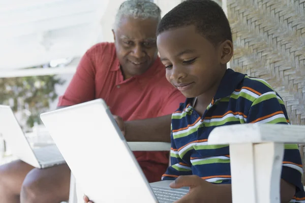 African American grandfather and grandson looking at laptop