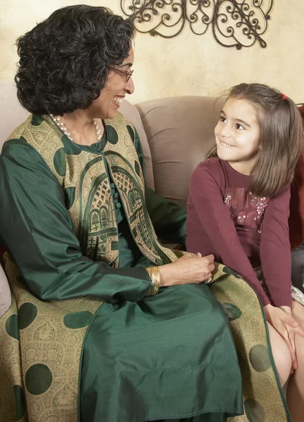 Indian grandmother and granddaughter smiling at each other