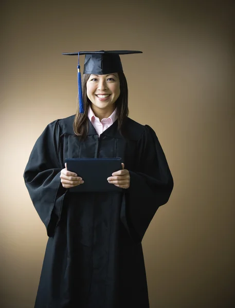 Asian woman wearing graduation cap and gown