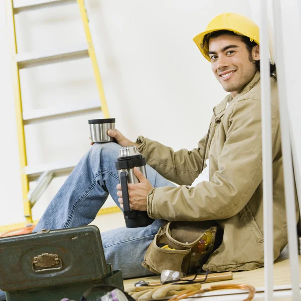 Mixed Race male construction worker drinking coffee