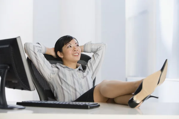 Asian businesswoman with feet on desk