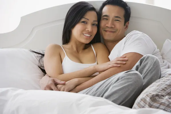 Asian couple hugging in bed