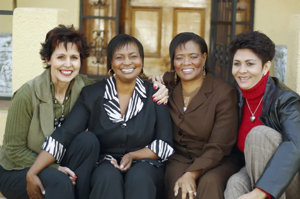 Multi-ethnic women sitting on porch steps