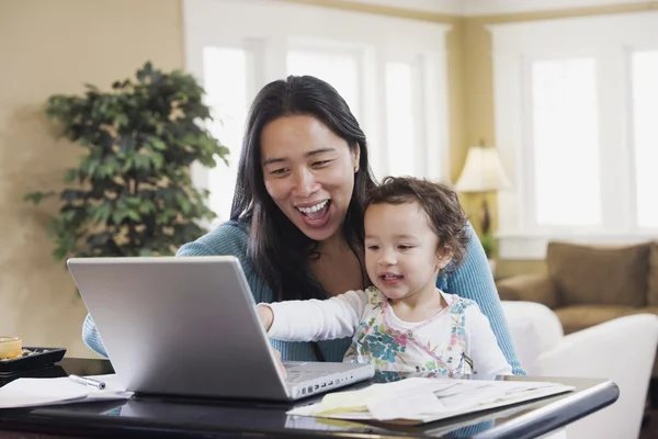 Mixed Race mother and baby looking at laptop