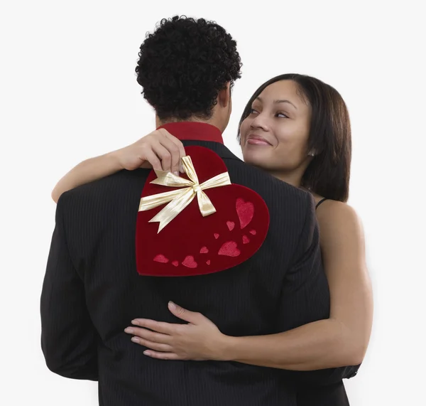 African woman holding valentine\'s gift and hugging boyfriend