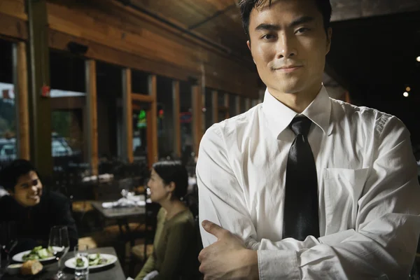 Asian waiter with arms crossed