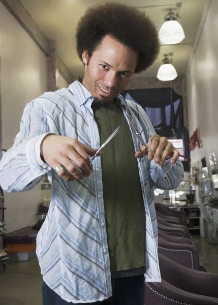 Mixed Race male hair stylist holding scissors