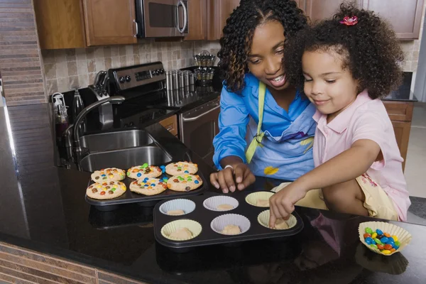 African mother and daughter making cupcakes