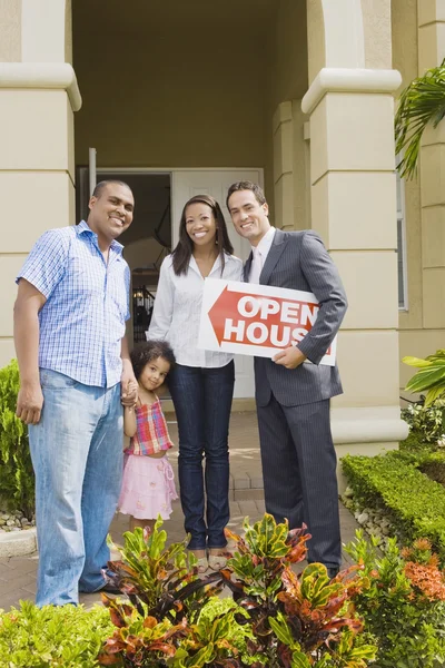Hispanic real estate agent and African family in front of house