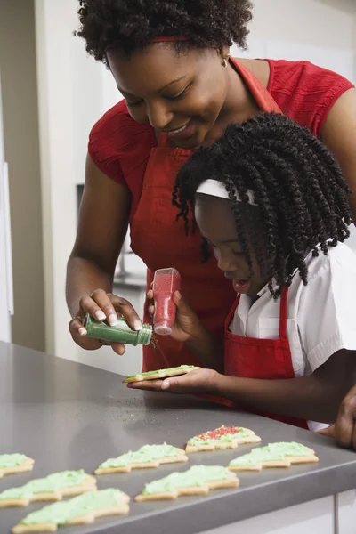 African mother and daughter decorating cookies