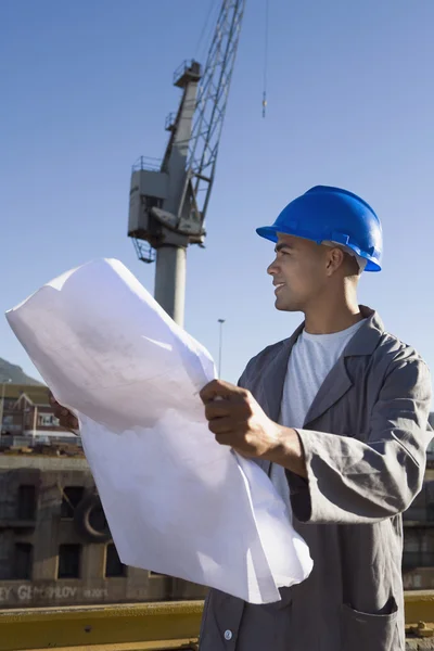 African American construction worker holding blueprints