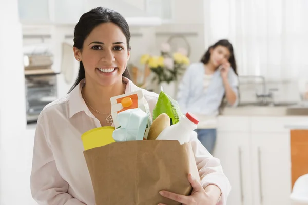 Hispanic woman holding grocery bag