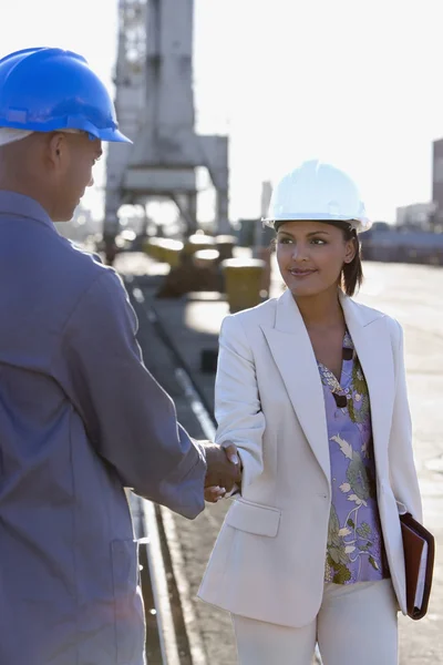 African American businesswoman and construction worker shaking hands
