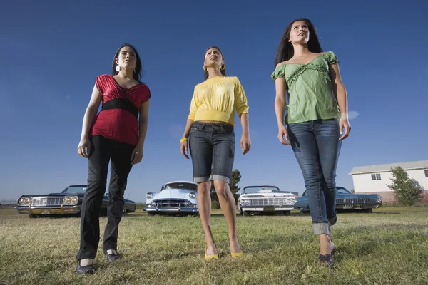 Multi-ethnic women in front of low rider cars
