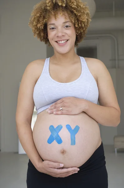 Pregnant African woman with XY painted on belly