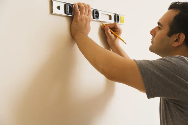 Hispanic man measuring with level on wall