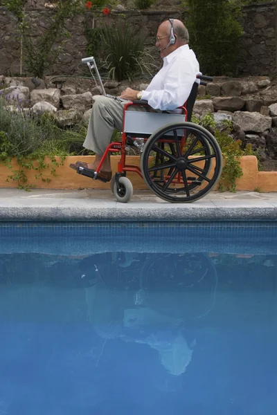 Senior man using laptop in wheelchair