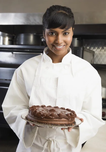 Mixed Race female pastry chef holding cake