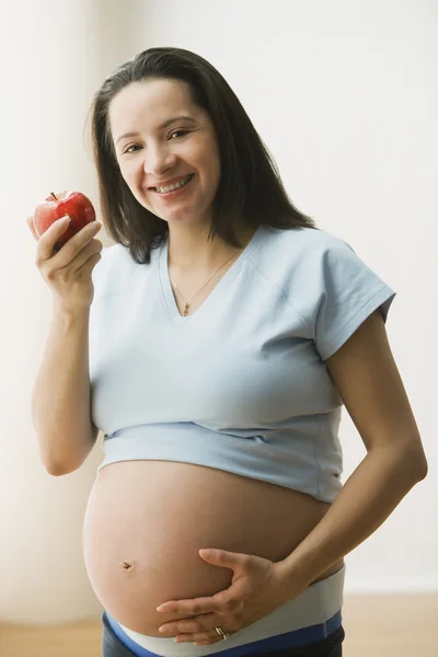 Pregnant woman holding apple and smiling