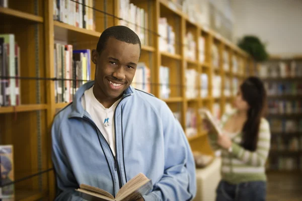African teenage boy reading in school library